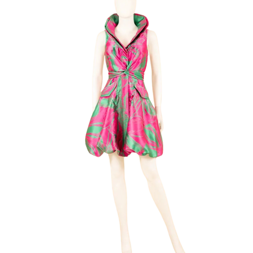 A stunning yarn-dyed brocade bubble dress displayed on a mannequin, featuring a wired collar with a cross-tie detail and a striking fuchsia and green color contrast.