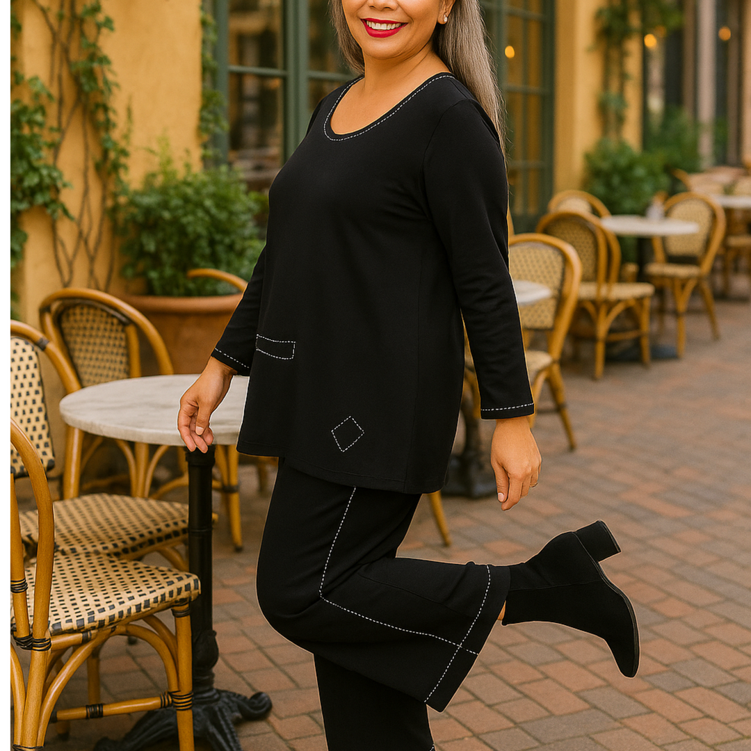 Woman in black outfit posing outdoors with chairs and tables in the background