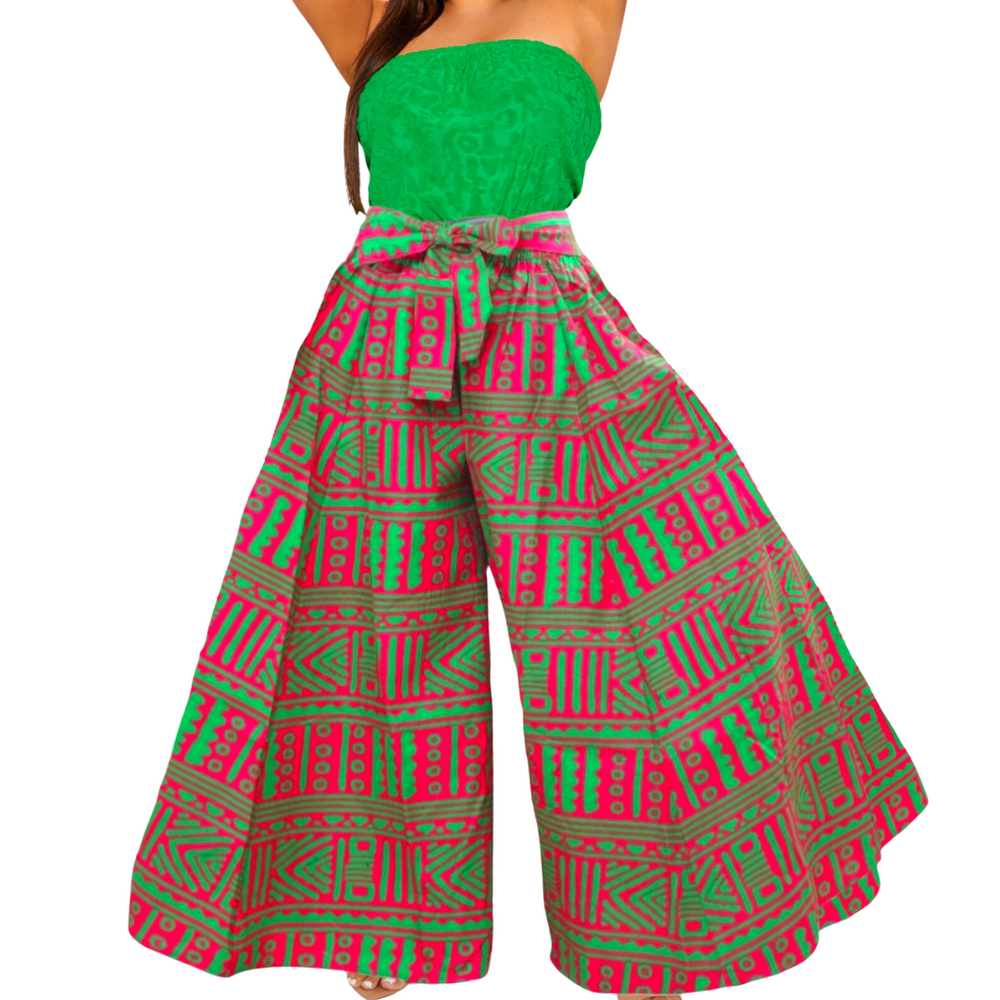 A model wearing long wide-leg palazzo pants in a pink and green color tone, with side pockets and an elastic waist with a sash. A matching head scarf is included.