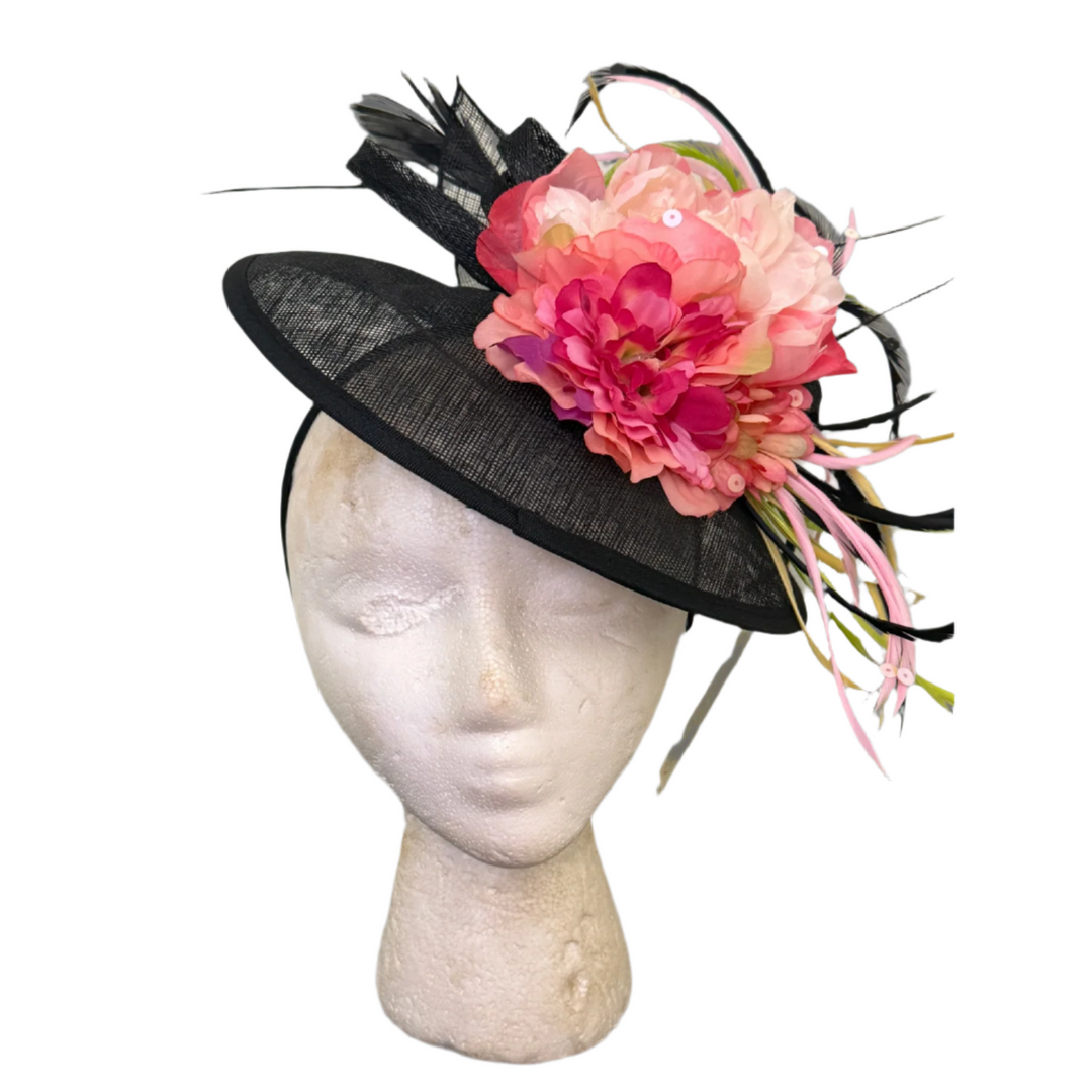 Black hat with pink flowers on a mannequin head against a gray background