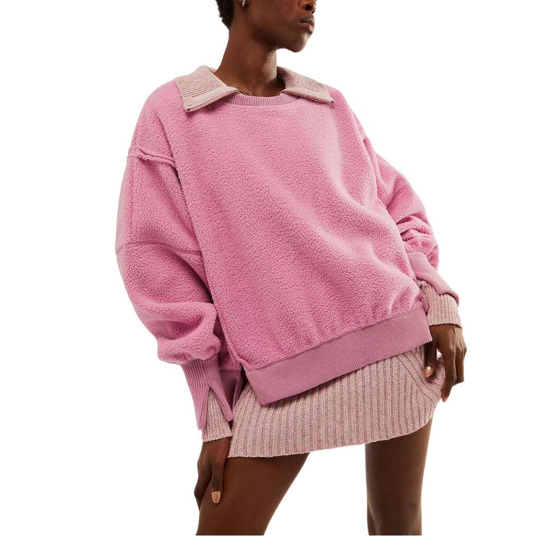 A woman wearing a pink turtleneck sweatshirt with a crew neckline and long sleeves.