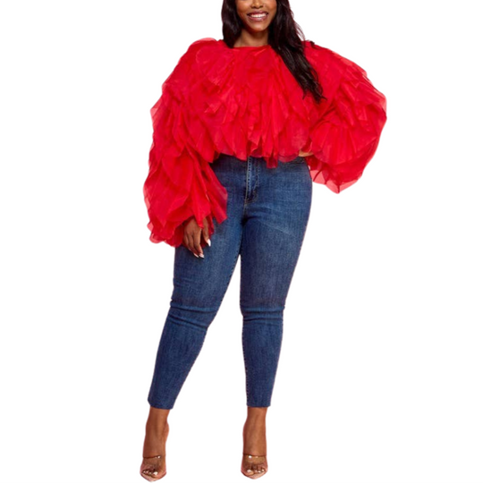 A woman wearing a red ruffle tulle crop top with long sleeves, paired with blue jeans.