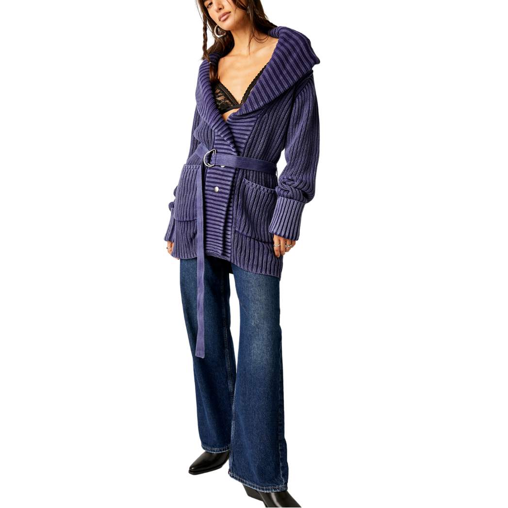 Woman wearing a purple ribbed cardigan and blue jeans on a white background