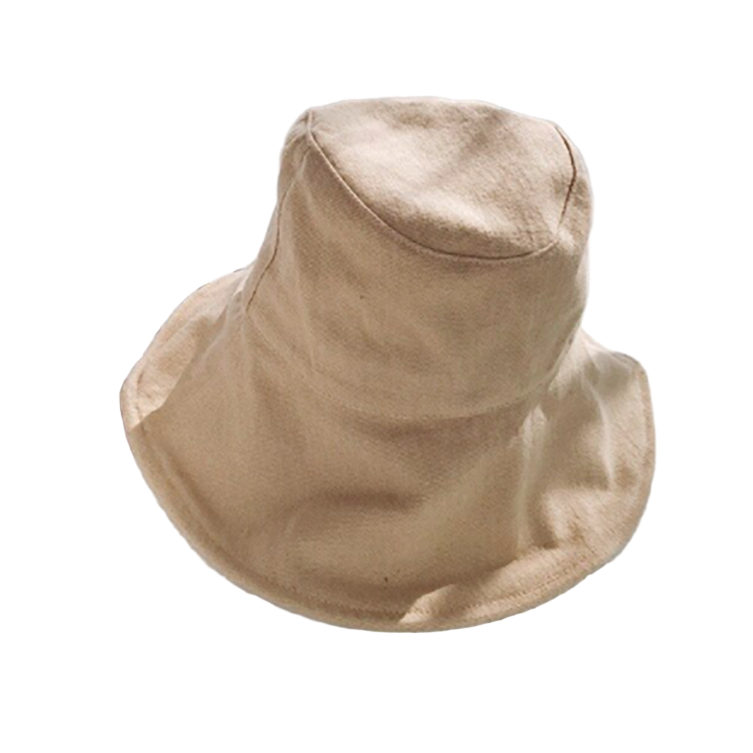 Beige bucket hat on a white surface with a magazine underneath