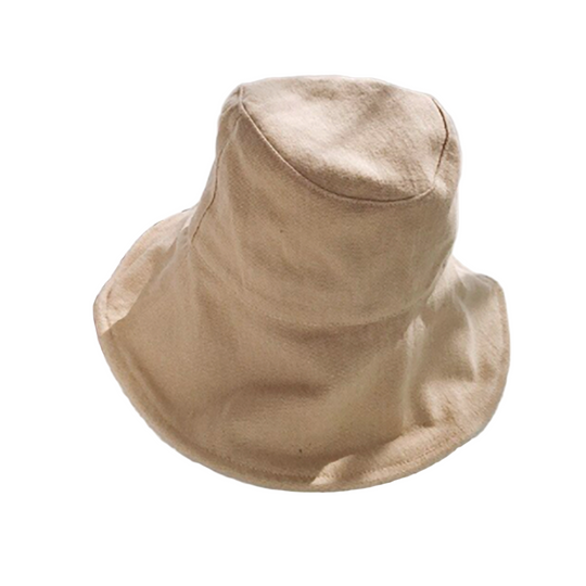 Beige bucket hat on a white surface with a magazine underneath