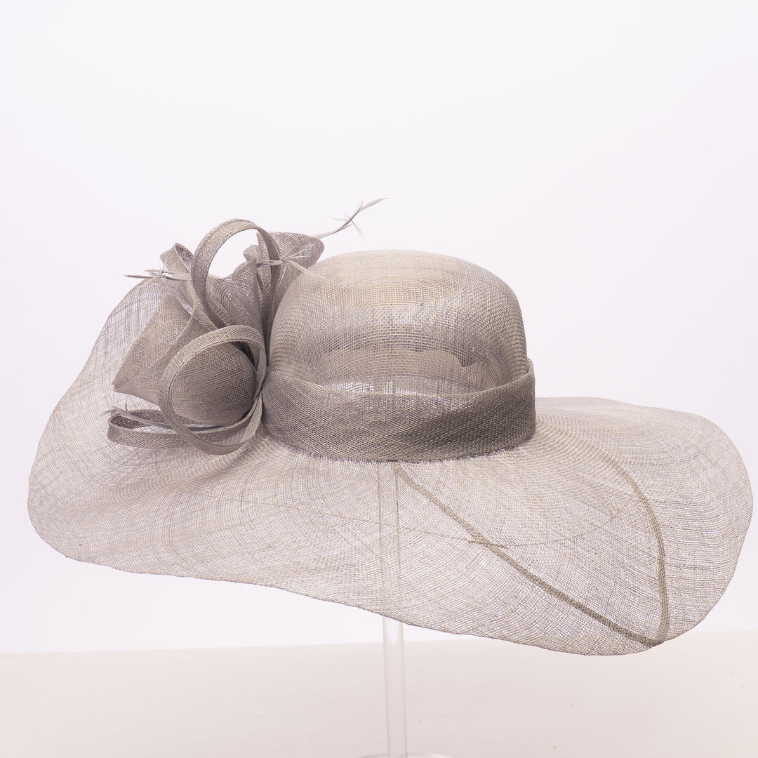 A light gray wide-brimmed fascinator hat with a matching ribbon bow and veil, displayed on a clear stand against a white background.