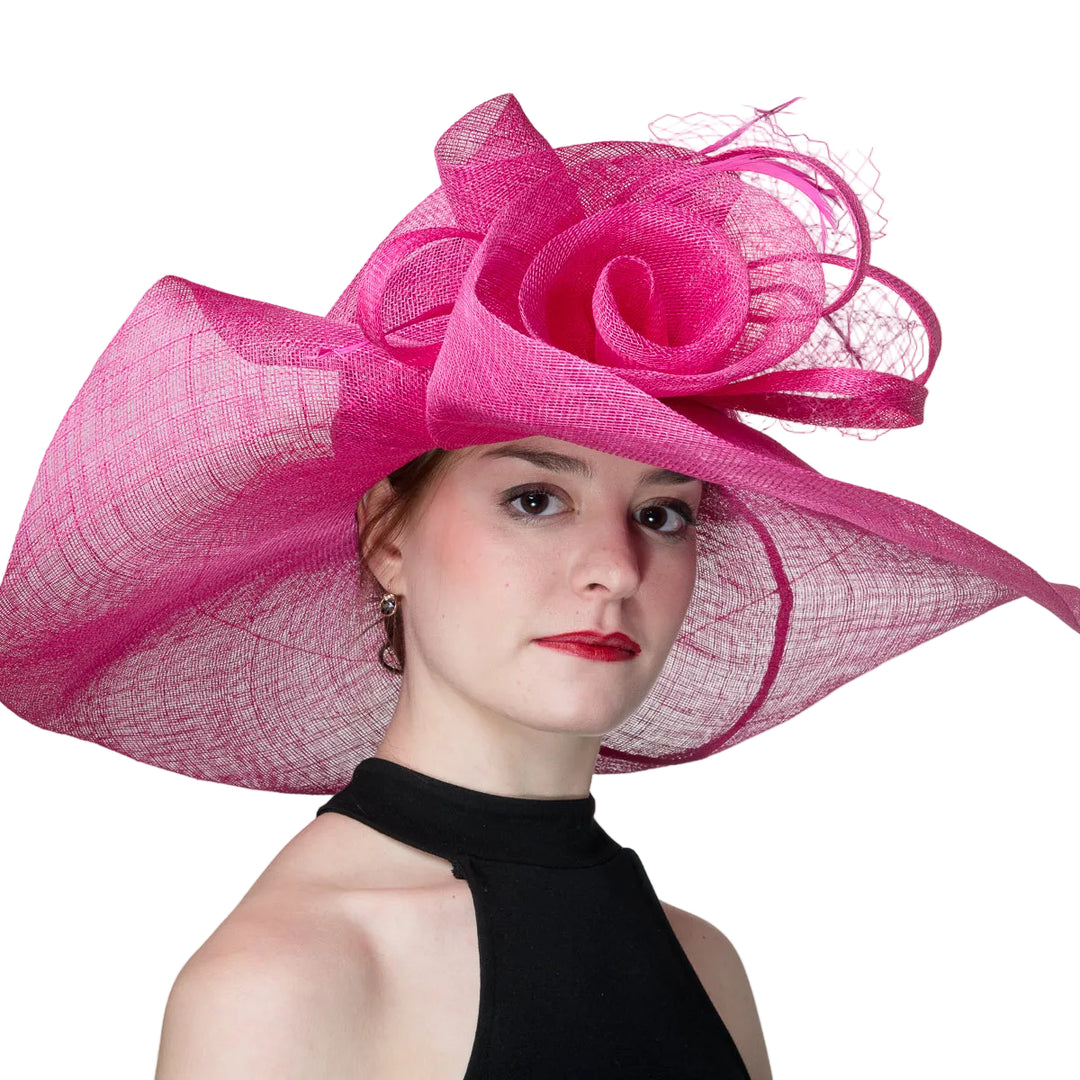 Woman wearing a large pink hat with a floral design on a plain background