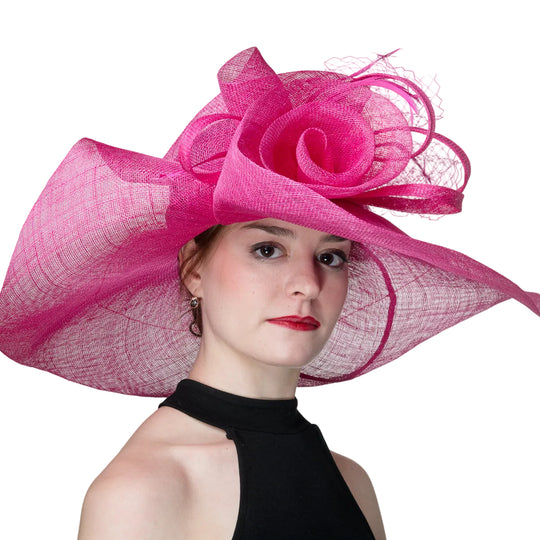 Woman wearing a large pink hat with a floral design on a plain background