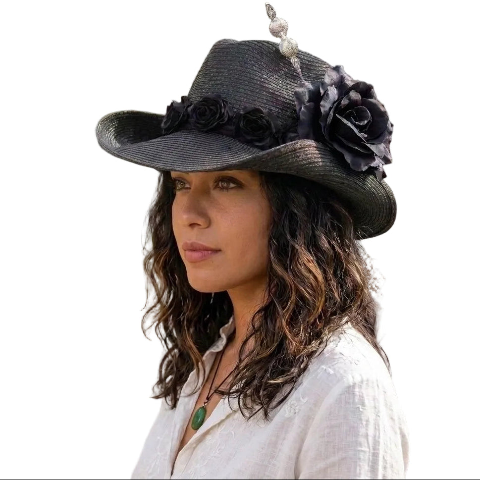 Woman wearing a black hat with floral decorations outdoors.