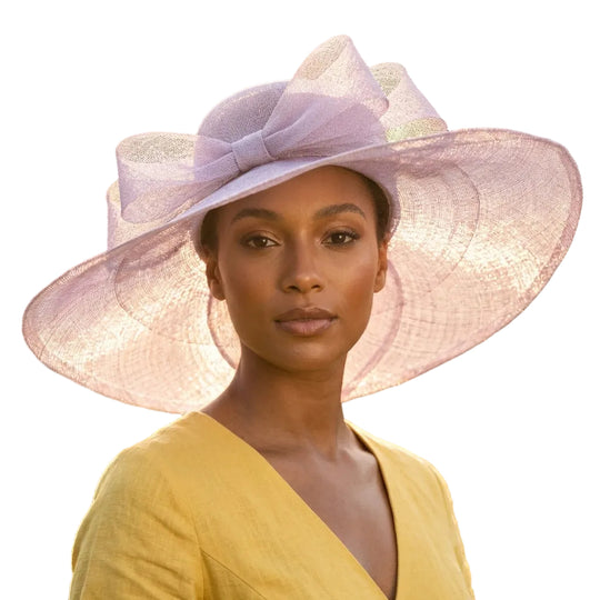 Woman wearing a large pink hat with a blurred natural background