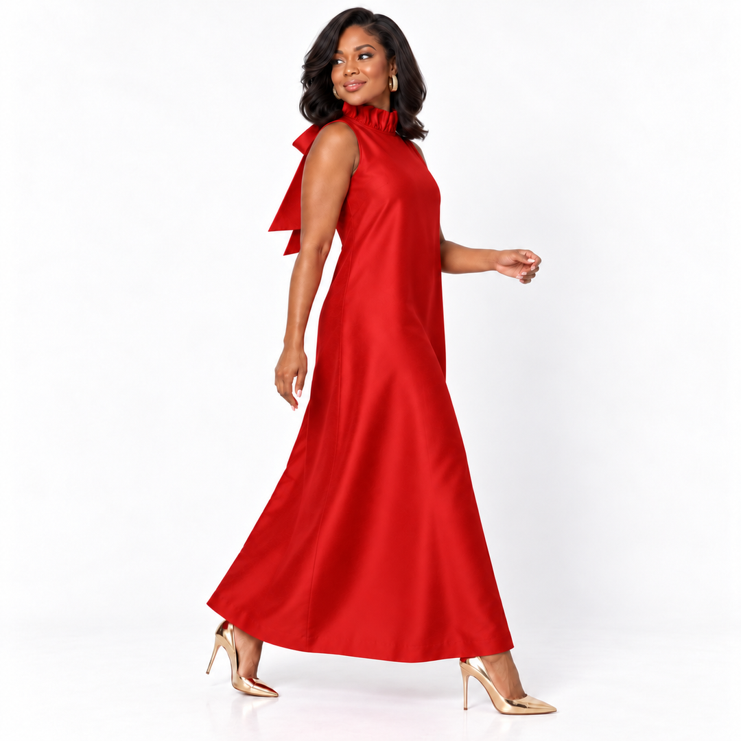 A woman modeling a sleeveless red maxi dress with a high ruffled neckline and a flowing skirt, paired with nude high heels, against a plain white studio background.
