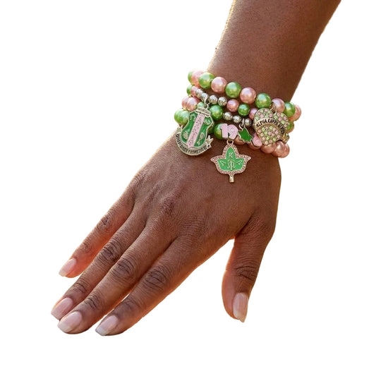 Hand wearing multiple colorful bracelets on a wooden surface with greenery in the background