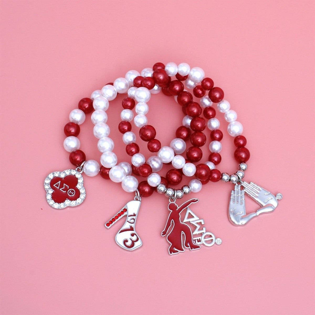 Red and white beaded bracelet with charms on a pink background