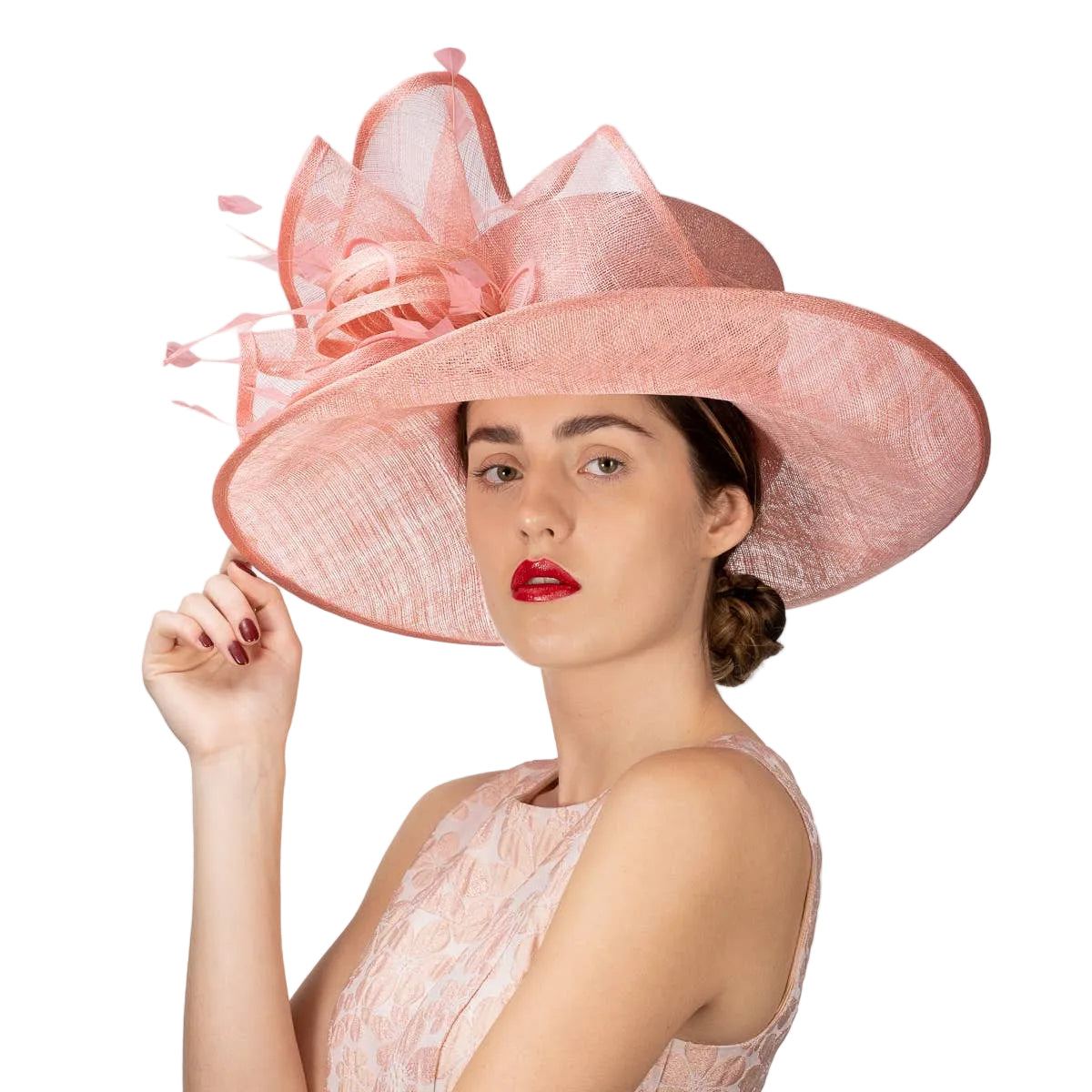 Woman wearing a large pink hat with decorative elements on a plain background