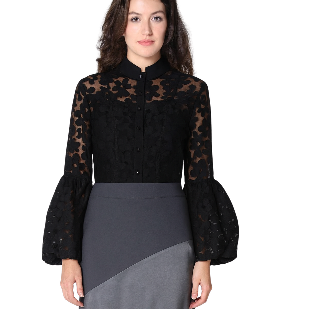 Woman wearing a black blouse with sheer sleeves and a gray skirt on a white background