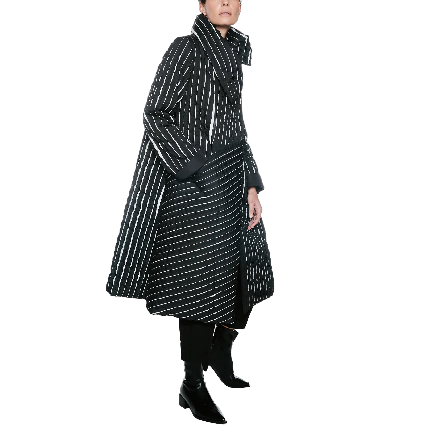 A model wearing a long black coat with thin white vertical stripes, paired with black pants and black ankle boots, photographed against a plain white studio background.