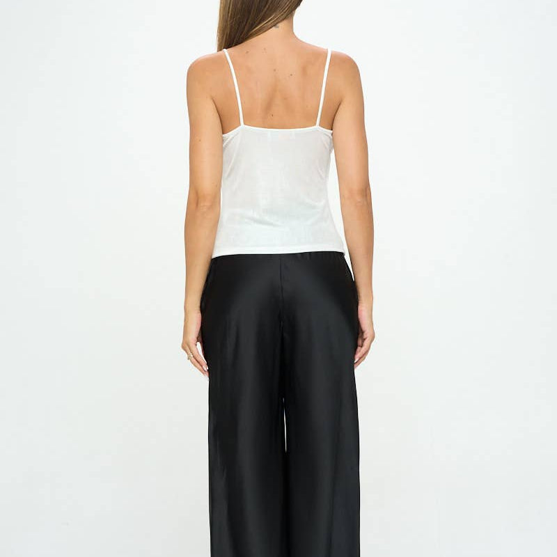 Woman wearing a white top and black pants on a white background