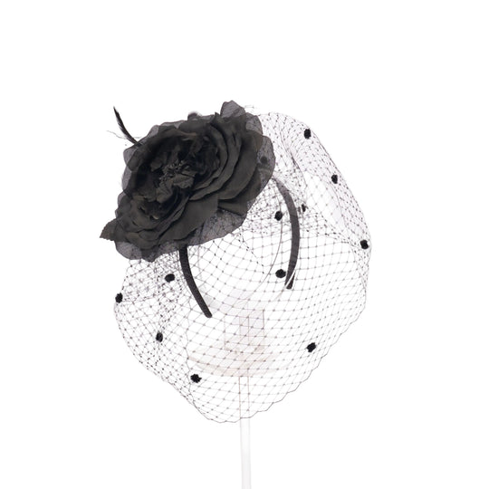 Black flower headpiece with a net veil on a white background