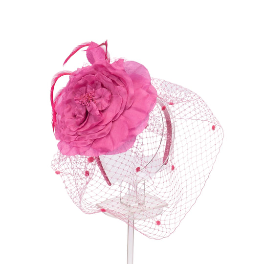 Pink floral headpiece with a net veil on a white background