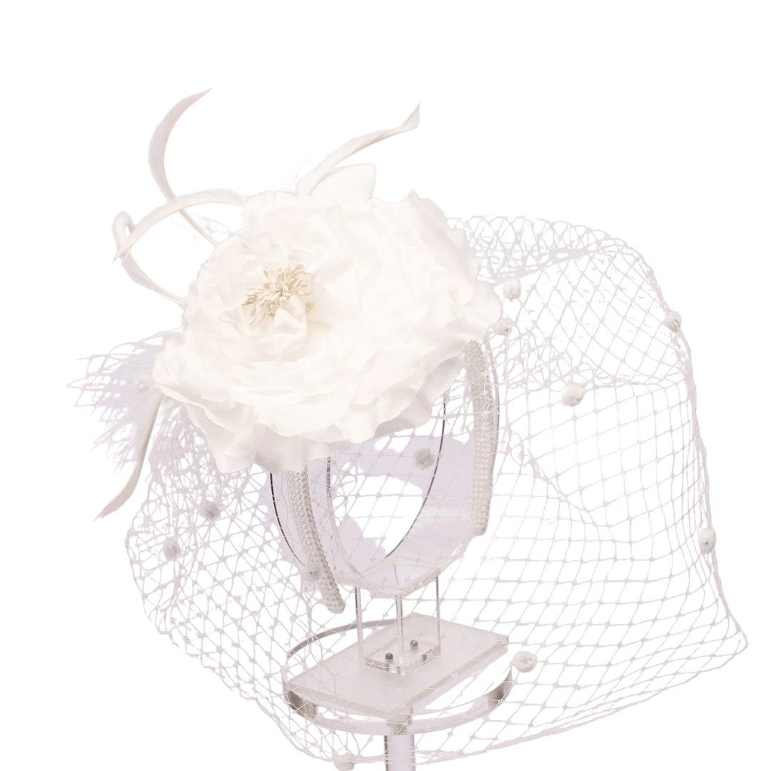 White floral headpiece on a clear stand against a light gray background
