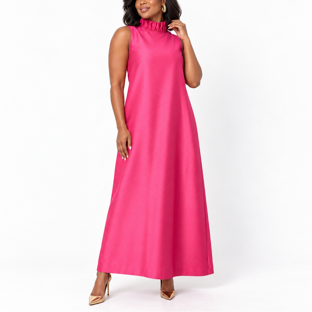 A woman modeling a sleeveless, high-neck, floor-length magenta dress against a plain white studio background.