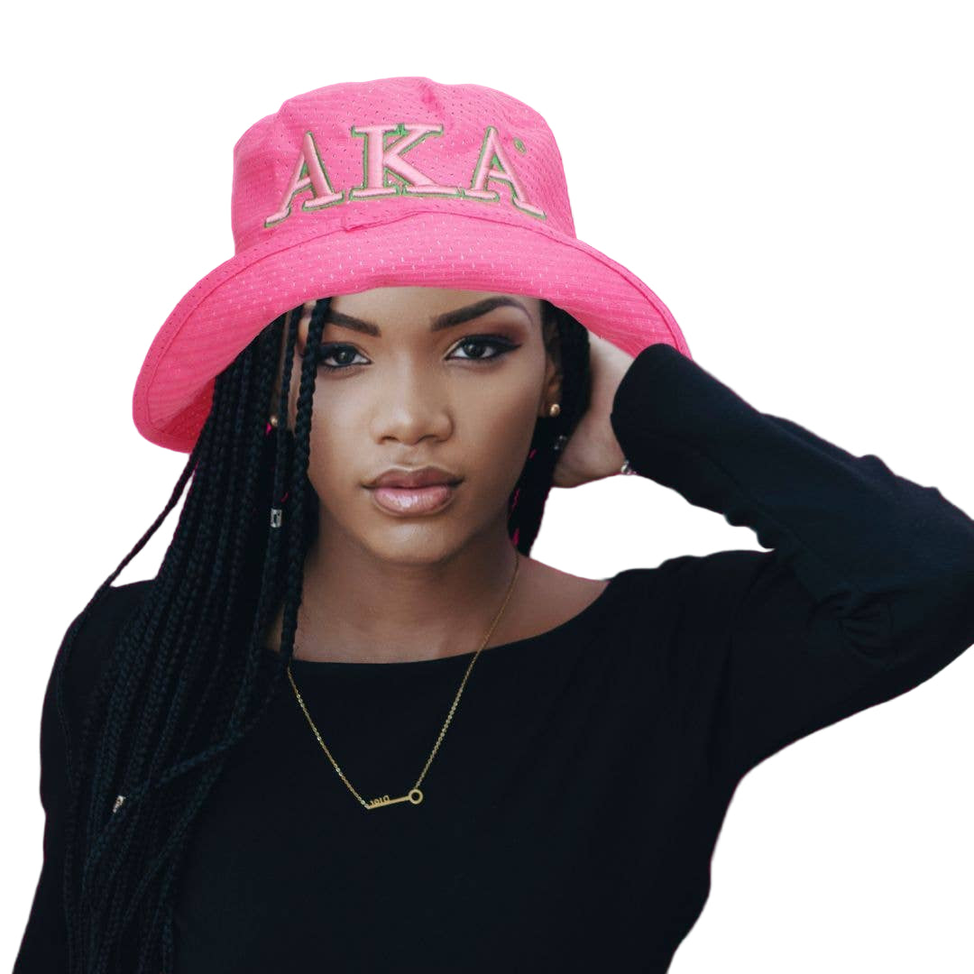 Person wearing a pink 'AKA' cap against a pink background