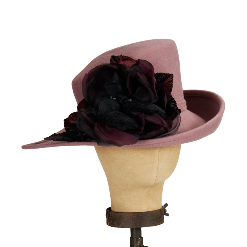 Pink hat with black flowers on a mannequin head against a white background