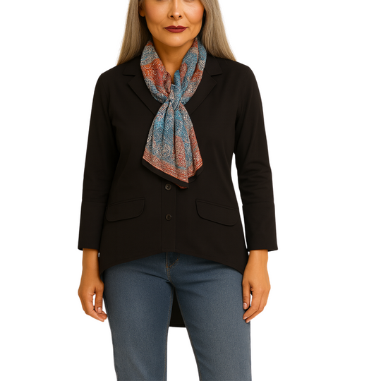 Woman wearing a black blazer and blue jeans with a colorful scarf on a white background