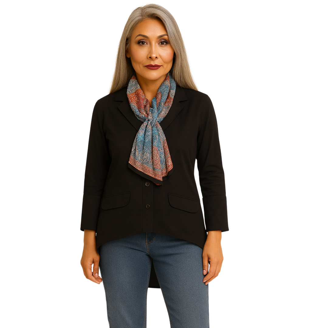 Woman wearing a black blazer and blue jeans with a colorful scarf on a white background