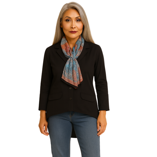 Woman wearing a black blazer and blue jeans with a colorful scarf on a white background