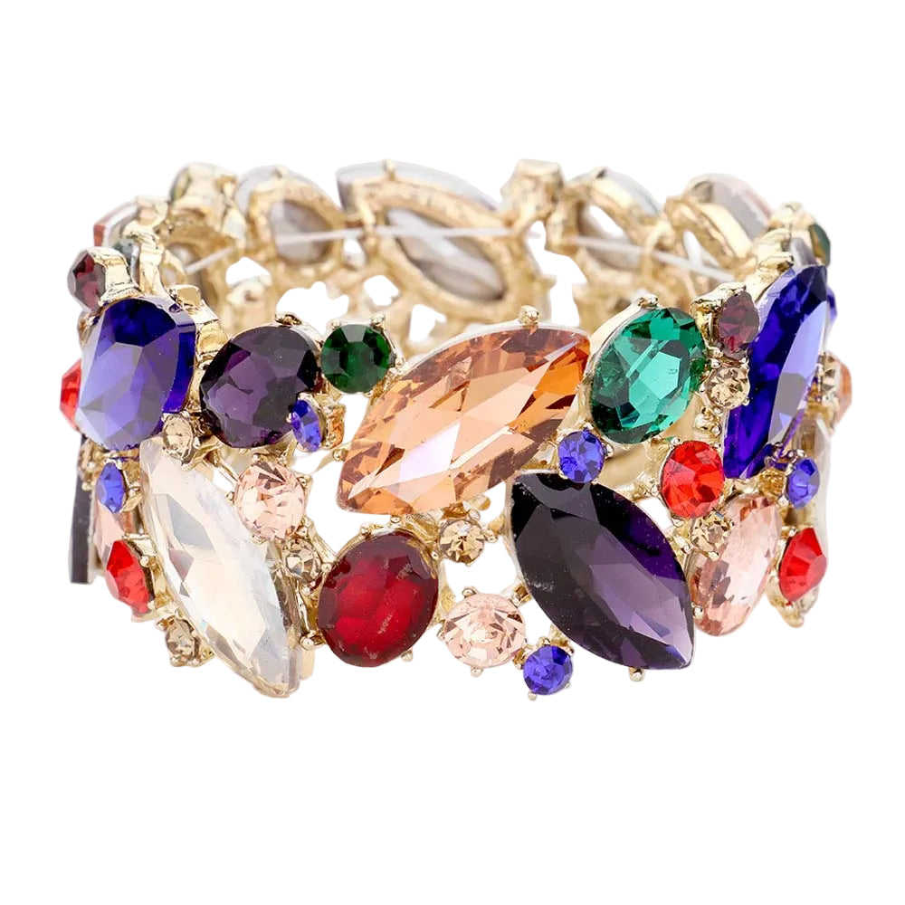 A wide gold-tone cuff bracelet embellished with a dense arrangement of marquise, oval, and round crystals in multiple colors including purple, blue, green, red, pink, and peach, set against a light gray background.