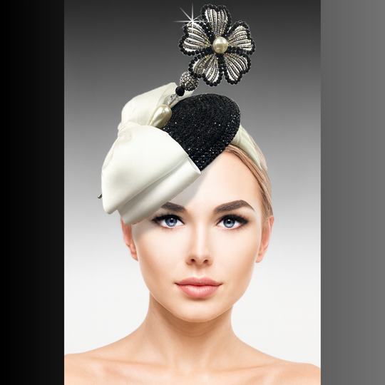 Woman wearing a decorative headpiece with a black and white design on a gray background