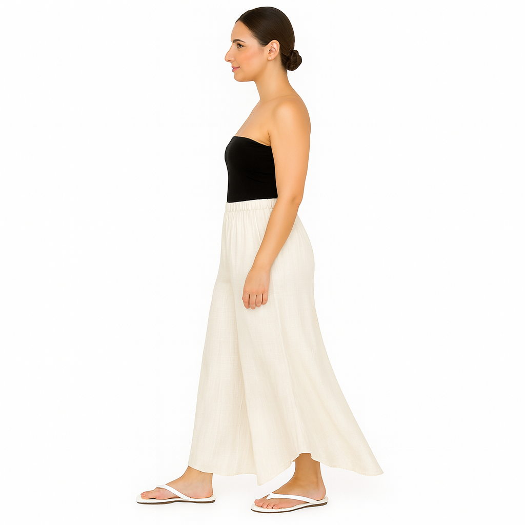 Woman wearing a black strapless top and white flowing skirt on a white background