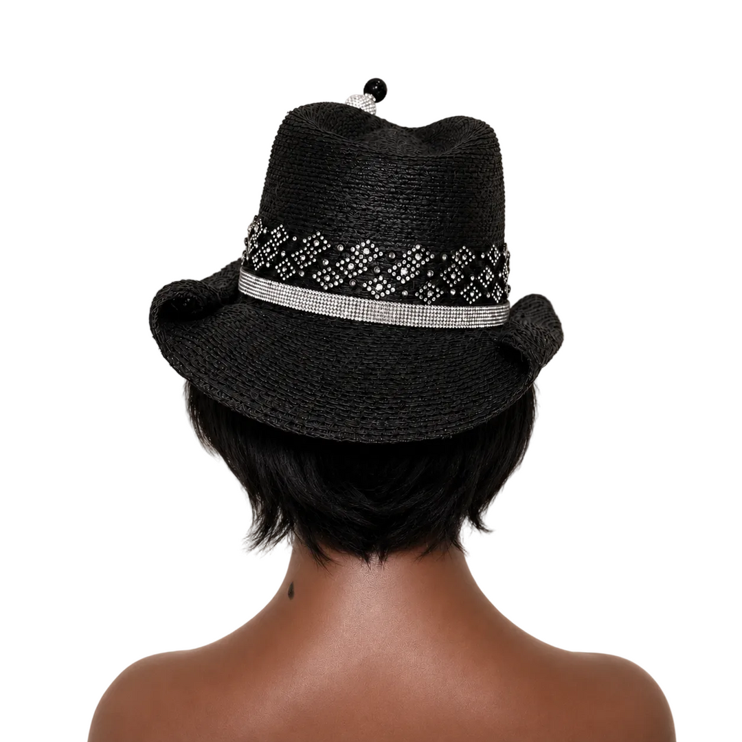 Black straw hat with decorative band worn by a person on a beige background