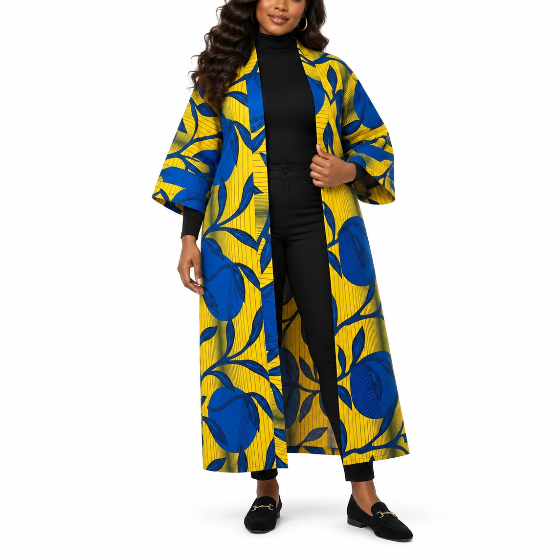 A woman modeling a long open-front coat with a bold blue and yellow floral print over a black outfit, photographed against a plain white studio background.