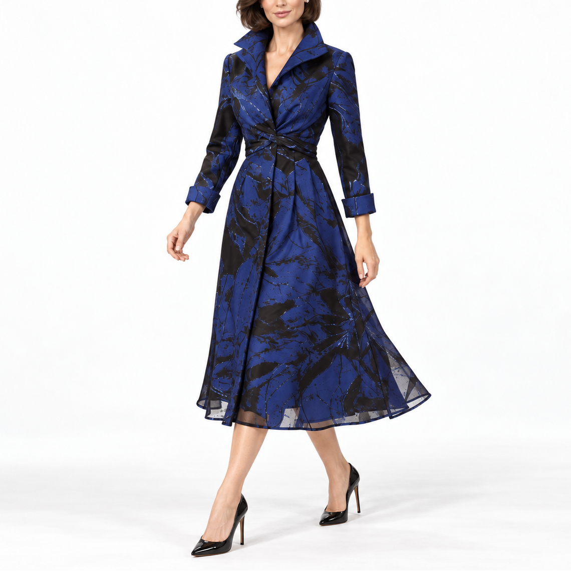 A woman modeling a blue and black patterned midi wrap coat dress with a waist tie, shown against a plain white studio background.