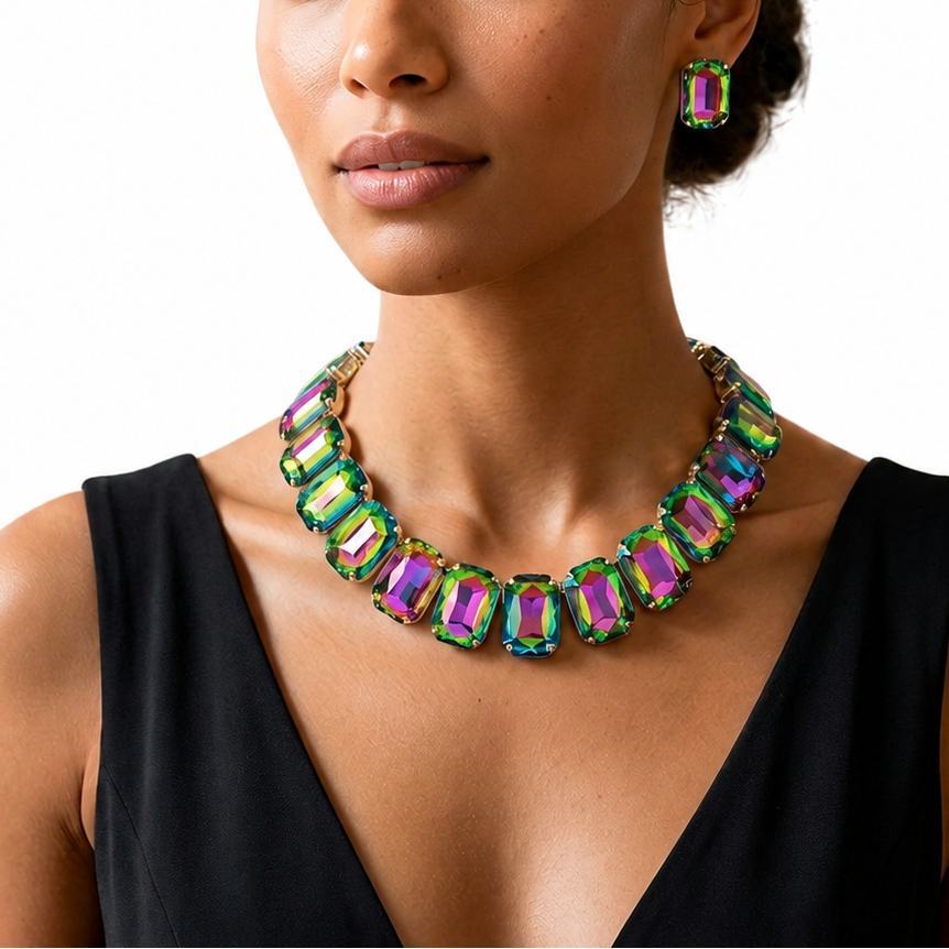 A woman wearing a chunky statement necklace and matching drop earrings made of iridescent green and purple rectangular gemstones, set against a plain white background.