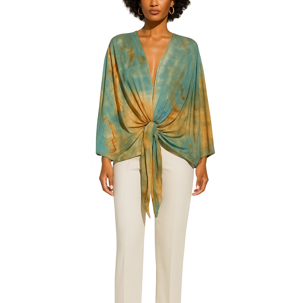 Woman wearing a green and gold patterned top with white pants on a white background