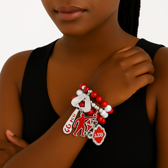 Person wearing a bracelet with multiple charms on a plain background