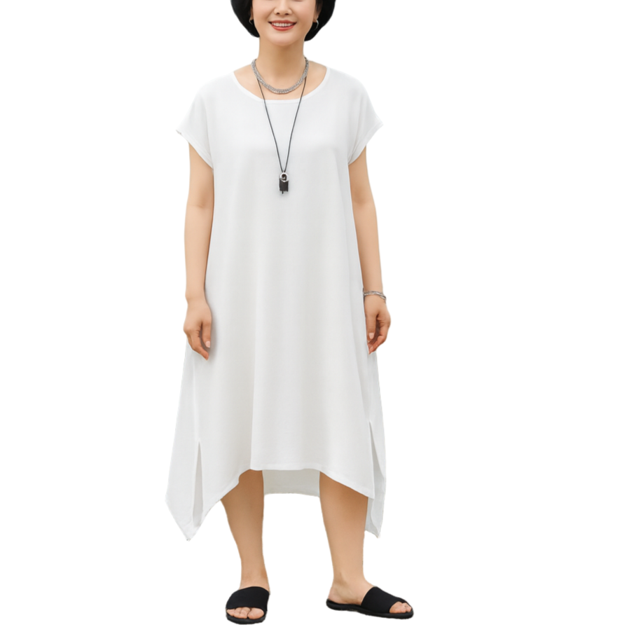 Woman in a white dress standing on a beach with mountains in the background