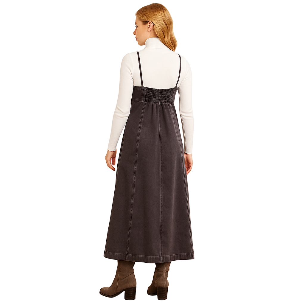 Woman wearing a long dark dress with straps on a plain background