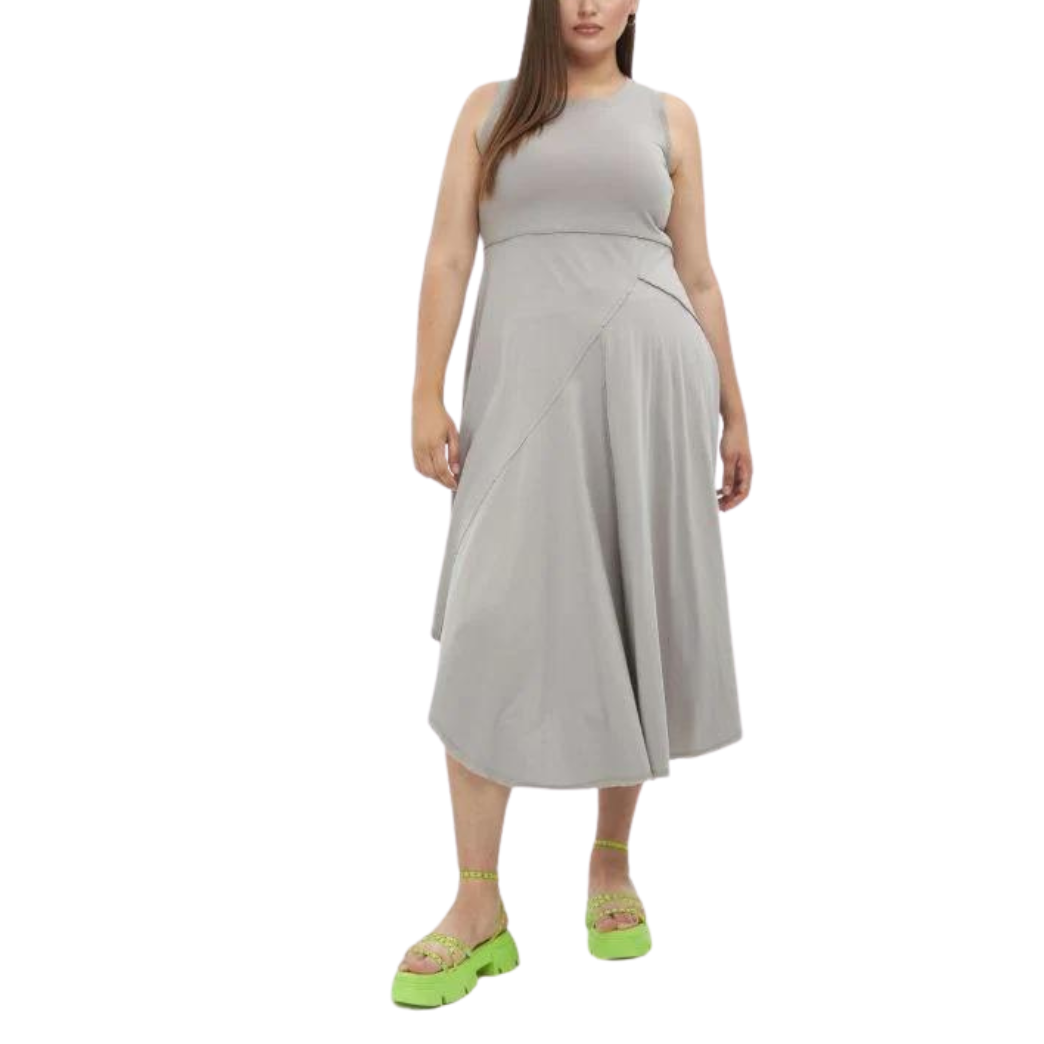 A woman wearing a beige asymmetrical hem pullover maxi dress with a round neckline, photographed from the waist down.