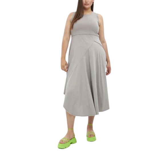 A woman wearing a beige asymmetrical hem pullover maxi dress with a round neckline, photographed from the waist down.