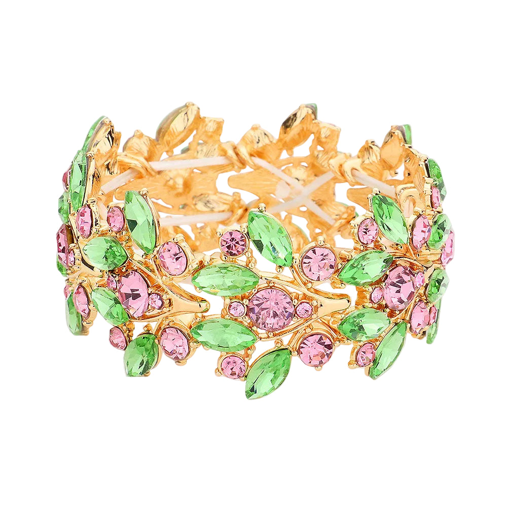 Gold bracelet with green and pink gemstones on a light gray background