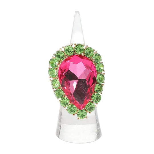 Jewelry ring with a pink teardrop gem and green gemstones on a white background