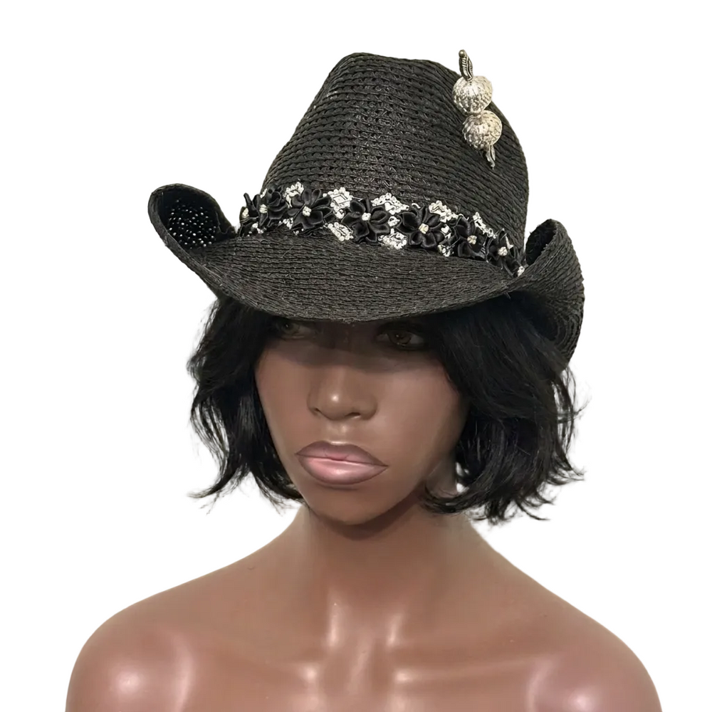 Black straw cowboy hat with decorative elements on a mannequin head against a beige background