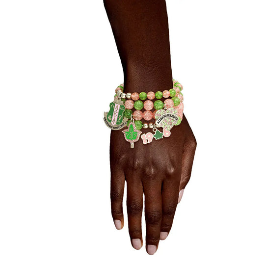 Hand wearing multiple colorful bracelets with charms on a white background