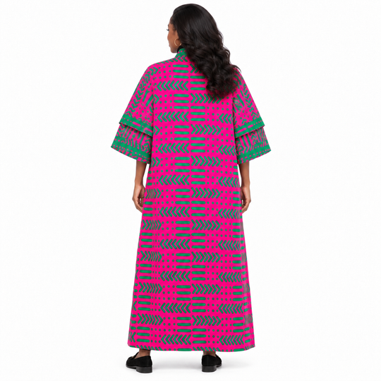 A woman viewed from the back wearing a long kaftan dress with a vibrant pink and green geometric pattern and layered elbow-length sleeves, set against a plain white background.