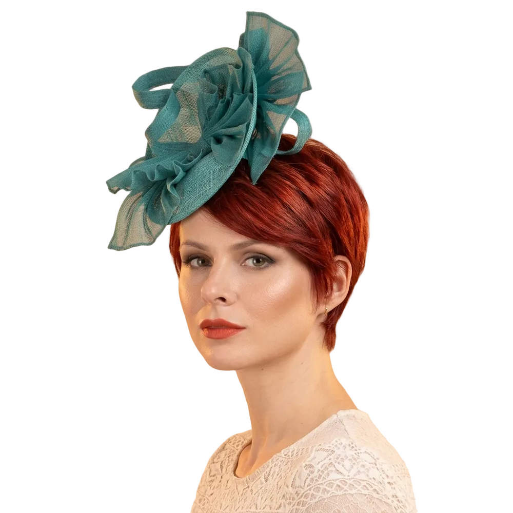 Woman wearing a teal decorative headpiece against a beige background