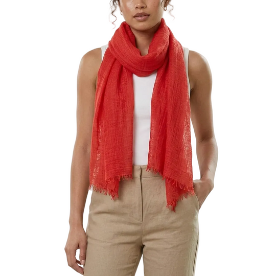 Person wearing a red scarf, white top, and beige pants on a white background